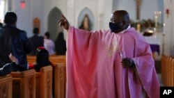 The Rev. Athanasius Abanulo waves to his parishioners after Mass, at Immaculate Conception Catholic Church in Wedowee, Ala., Dec. 12, 2021.
