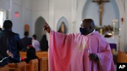 The Rev. Athanasius Abanulo waves to his parishioners after Mass, at Immaculate Conception Catholic Church in Wedowee, Ala., Dec. 12, 2021.