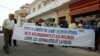 A group of fifty people hold a banner reading "Shed light on the death of Deyda Hydara. Stop assassinations and violence against journalists and the press," during a protest in front of Gambia's high commission, 22 December 2004 in Dakar.