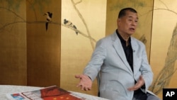 FILE - Hong Kong media tycoon Jimmy Lai gestures next to a copy of Apple Daily's July 1 edition during an interview in Hong Kong, July 1, 2020.