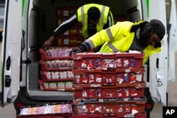 Volunteers from the charity 'The Felix Project' unload bread at their storage hub in London. The group helps small food kitchens get goods they can use to feed people who do not have enough to eat. (AP Photo/Frank Augstein)