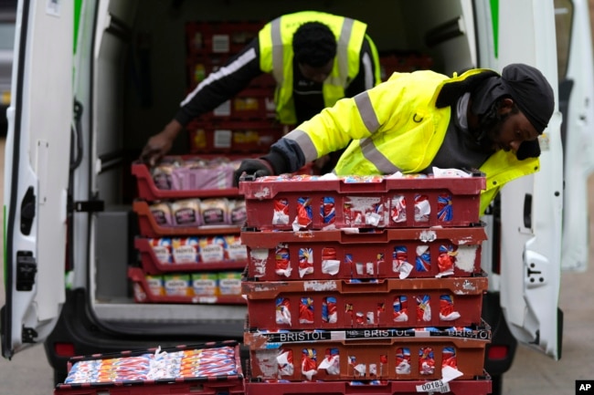 Volunteers from the charity 'The Felix Project' unload bread at their storage hub in London. The group helps small food kitchens get goods they can use to feed people who do not have enough to eat. (AP Photo/Frank Augstein)