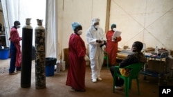 FILE - A COVID-19 patient, right, is seen to by health workers at Queen Elizabeth Central Hospital in Blantyre, Malawi, Jan. 30, 2021. 