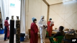 FILE - A COVID-19 patient, right, is seen to by health workers at Queen Elizabeth Central Hospital in Blantyre, Malawi, Jan. 30, 2021. 