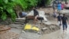 People walk along a street as a jeep is buried in the mud due to the flood at Teesta Bazaar in Kalimpong District, West Bengal, India, on Oct. 4, 2023.