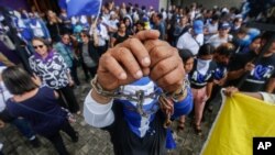 A man holds up his chained wrists during a memorial on the one year anniversary of a government crackdown on a Mother’s Day march, outside the Catedral in Managua, Nicaragua, Thursday, May 30, 2019. An international fact-finding group last year said…
