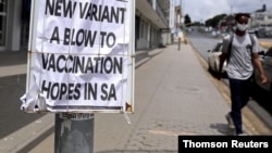 FILE - A man walks past newspaper billboards during the coronavirus disease (COVID-19) outbreak in Johannesburg, South Africa, Feb. 8, 2021.