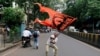 FILE - A man waves a flag as he blocks a road during a protest, organized by Maharashtra state's Maratha community, to press their demands for reserved quotas in government jobs and college places for students in Mumbai, India, July 25, 2018. 