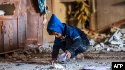 Palestinski dječak skuplja komadiće otpada nakon izraelskog bombardiranja Rafaha u južnom pojasu Gaze 22. decembra 2023.
