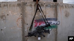 Dua senapan M-16 tergantung di dinding dengan grafiti yang menampilkan bendera Palestina di Pusat Pelatihan Perang Kota IDF di pangkalan militer Zeelim, Israel selatan, 10 Februari 2022. (Foto: AP)