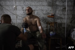 This picture taken by the press service of Ukraine's 24th Mechanized Brigade on July 9, 2024, and released on July 12, 2024, shows a combat medic giving treatment to an injured serviceman on the front line near Chasiv Yar, Donetsk region.