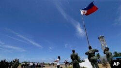 Warga Filipina(tengah) dan tentara melakukan upacara pengibaran bendera saat Jenderal Gregorio Pio Catapang, Kepala Militer Filipina berkunjung ke pulau Pag-asa, salah satu dari kepulauan Srpatly di laut Cina Selatan, selatan Palawan, Filipina, 11 Mei 2015 (Foto: dok).