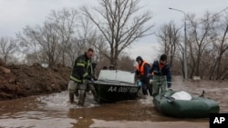 Emergency workers push their boats in a flooded area in Orenburg, Russia, Wednesday, April 10, 2024. Russian officials are scrambling to help homeowners displaced by floods, as water levels have risen in the Ural River. 