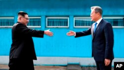 North Korean leader Kim Jong Un, left, prepares to shake hands with South Korean President Moon Jae-in over the military demarcation line at the border village of Panmunjom in Demilitarized Zone Friday, April 27, 2018. Their discussions will be expected t