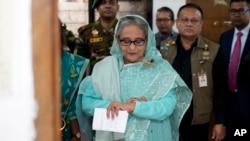 FILE - Sheikh Hasina checks her watch as she waits for the official opening time to cast her vote in Dhaka, Bangladesh, Jan. 7, 2024.