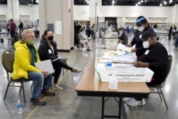 FILE - Election workers, right, verify ballots as recount observers, left, watch during a Milwaukee hand recount of presidential votes at the Wisconsin Center, in Milwaukee, Wisconsin, November 20, 2020.