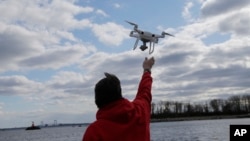 FILE- A drone operator helps to retrieve a drone after photographing over Hart Island in New York, April 29, 2018.