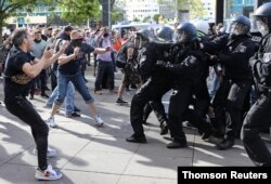 Police officers pepper-spray protesters during a demonstration at Alexanderplatz, amid the spread of the coronavirus disease, in Berlin, Germany, May 9, 2020.