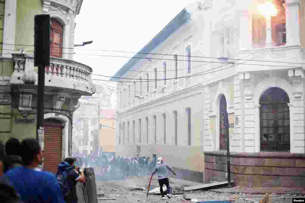 Un manifestante mira una bomba de gasolina arrojada a un edificio durante los enfrentamientos con la policía antidisturbios.