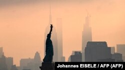 La Statue de la Liberté est vue devant l'Empire State Building au lever du soleil le 9 juillet 2020 à New York.