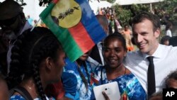 French President Emmanuel Macron, right, meets residents, one with the independence Kanak flag in her hair, on Ouvea Island, off New Caledonia, May 5, 2018.