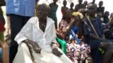 Monica Yom Kulang (with broken arm) sits under a desert date tree with her family members in Malek village, Jonglei state, South Sudan. (Deng Ghai Deng/VOA) 