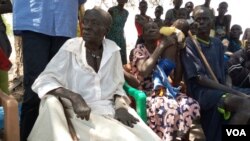 Monica Yom Kulang (with broken arm) sits under a desert date tree with her family members in Malek village, Jonglei state, South Sudan. (Deng Ghai Deng/VOA) 