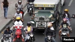 Pengendara sepeda motor dan angkutan jeepney saat menunggu lampu hijau di jalan di Paranaque, Metro Manila, 2 Maret 2016.