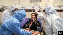 Medics treat a patient infected with the new coronavirus, at a hospital in Tehran, Iran, March 8, 2020. 