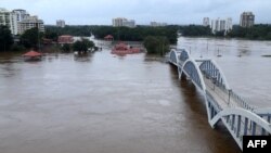 Des résidents indiens se tiennent sur le rivage alors que la rivière Periyar a été inondée après les pluies de mousson à Aluva, dans l’état indien du Kerala, le 16 août 2018. 