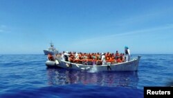 Para migran duduk di perahu mereka dalam operasi penyelamatan oleh kapal angkatan laut Italia di lepas pantai Sisilia (6/5).