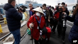 Tourists quarantined on the Diamond Princess cruise ship get some fresh air on the top deck of the ship, Feb. 13, 2020, in Yokohama, near Tokyo.