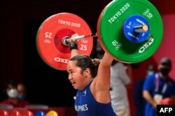 Hidilyn Diaz dari Filipina dalam kompetisi angkat besi 55kg putri pada Olimpiade Tokyo 2020 di Tokyo International Forum di Tokyo, 26 Juli 2021. (Vincenzo PINTO/AFP)