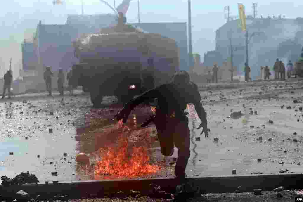 Protester whose clothes are on fire runs away from riot police during clashes in Taksim square in Istanbul on June 11, 2013.