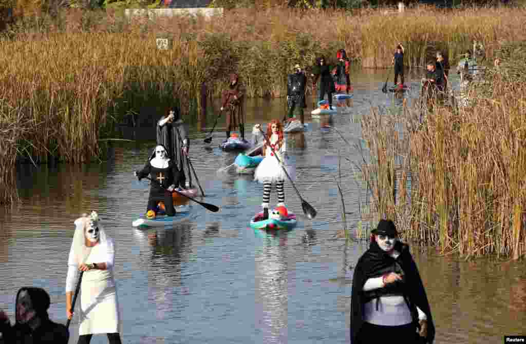 Para peserta mendayung papan selancar mereka selama tur SUP Halloween di Rackevei-Duna, di Szigetszentmiklos, Hungaria. (Reuters)&nbsp;