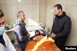 Presiden Suriah Bashar al-Assad mengunjungi seorang perempuan tua di Rumah Sakit Universitas Aleppo, Suriah, pada 10 Februari 2023. (Foto: via Reuters)