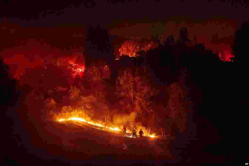 Firefighters contain a wildfire burning off Merrill Dr. in Moraga, California. Police have ordered evacuations as the fast-moving wildfire spread in the hills of the San Francisco Bay Area community.