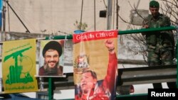 FILE - A Lebanese soldier stands beside posters of Hezbollah leader Sayyed Hassan Nasrallah and Venezuela's President Hugo Chavez on a bridge in Beirut, Dec. 1, 2006. 