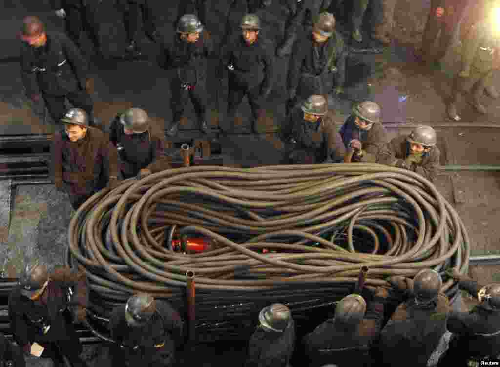 Para penambang mengangkut kabel-kabel untuk menjamin pasokan listrik di muka tambang batu bara Jiaojiazhai di Xinzhou, provinsi Shanxi di China, di mana 19 penambang tewas dalam ledakan gas, 8 November 2006. (Reuters)