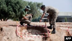 Greek-Cypriot soldiers look at what is believed to be a part of the Noratlas plane that was shot down by friendly fire during the Turkish invasion of Cyprus in 1974, near Nicosia, Aug. 6, 2015.