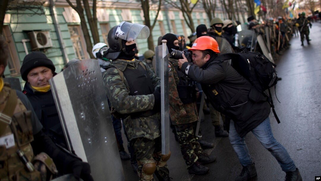 A photographer takes photos of an opposition supporter during a march toward parliament in Kyiv, Feb. 6, 2014.