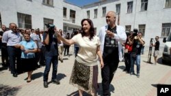 Albanian Prime Minister and leader of the Socialist party Edi Rama, right, and his wife Linda wave to supporters before casting their ballots at a polling station in Tirana, June 25, 2017.