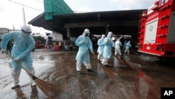 Workers clean the road outside shrimp market in Samut Sakhon, Bangkok, Jan. 25, 2021, as Thailand registered a new daily high of over 900 cases of the coronavirus at the province near the capital Bangkok, where a major outbreak occurred in December.