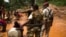 FILE - Former Seleka soldiers look at prospectors as they pan for gold near the open pit at the Ndassima gold mine in the Central African Republic, May 9, 2014.