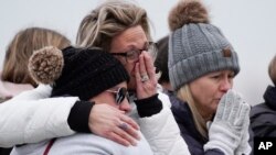 Mourners grieve at a memorial at Oxford High School in Oxford, Mich., Wednesday, Dec. 1, 2021. Authorities say a 15-year-old sophomore opened fire at Oxford High School, killing four students and wounding seven other people on Tuesday. (AP Photo/Paul Sancya)