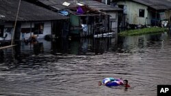 Children with a float swim through a swollen canal in Bangkok, Thailand, October 28, 2011.