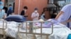 A patient on a hospital bed is pushed past a line of residents waiting to be tested at a fever clinic in Beijing, China, June 15, 2020. 