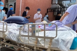 A patient on a hospital bed is pushed past a line of residents waiting to be tested at a fever clinic in Beijing, China, June 15, 2020.
