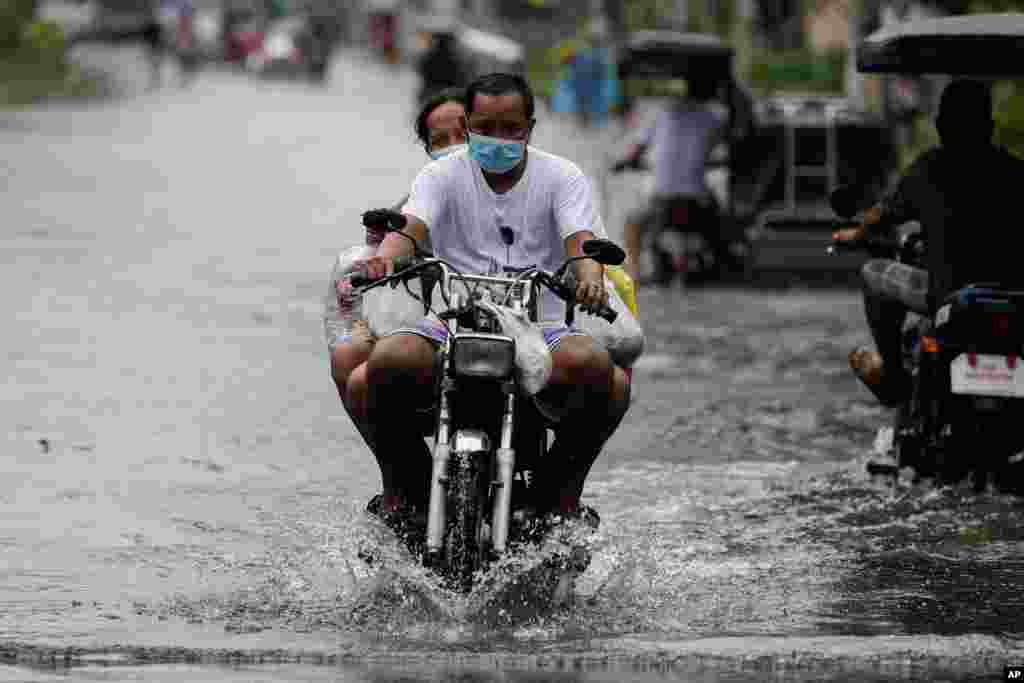 Warga mengendarai sepeda motor untuk melintasi jalanan yang tergenang banjir setelah topan Molave melanda provinsi Pampanga, Filipina utara dan memaksa ribuan penduduk mengungsi, Senin, 26 Oktober 2020.&nbsp;