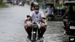 Residents on a motorcycle negotiate a flooded road due to Typhoon Molave in Pampanga province, northern Philippines, Monday, Oct. 26, 2020. A fast-moving typhoon forced thousands of villagers to flee to safety in provinces south of the Philippine…